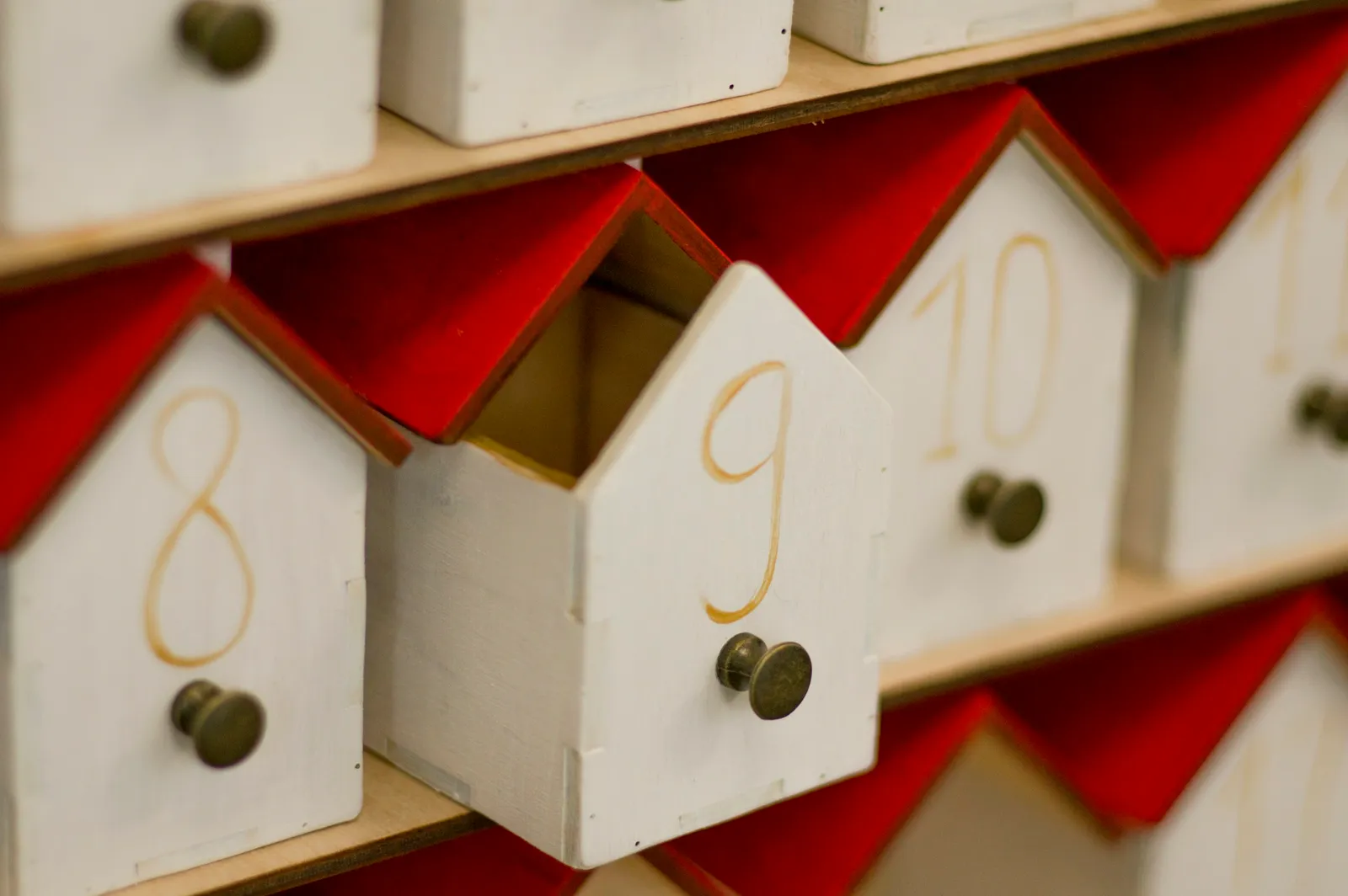 Handmade wooden advent calendar with numbered house-shaped drawers and red roofs