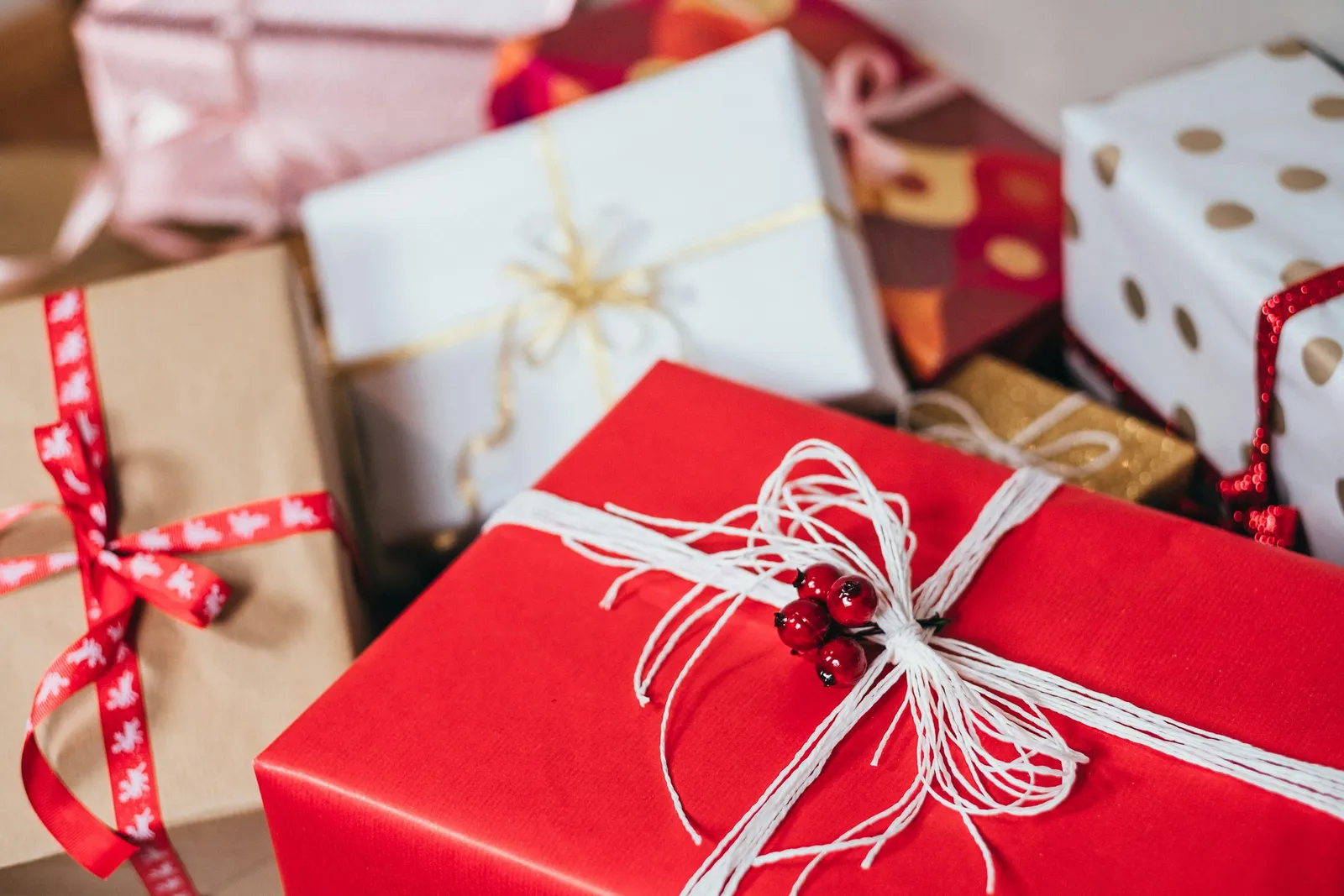 A pile of Christmas presents wrapped in red, white and kraft paper with ribbons