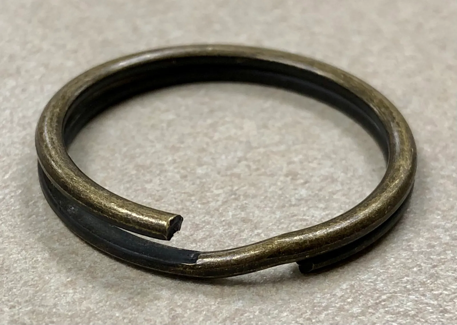A single brass-colored split keyring slightly opened, showing the double loop that holds keys