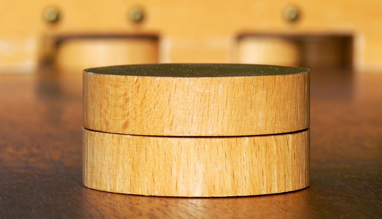 Red and blue weighted pucks resting on a polished wooden table shuffleboard surface